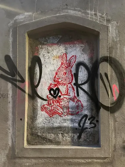 A quick tag over a stencil of a rabbit in an old wall niche. This shows the layering that happens in the streets, with artists painting over and around each other's work.