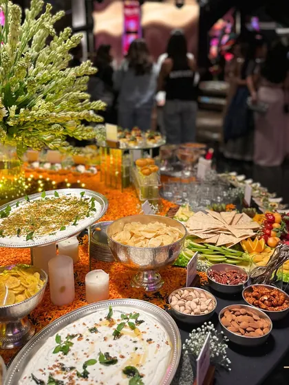 A wide view of a festive grazing table, perfect for a taash party. The spread includes a variety of Indian and Western snacks, dips, nuts, and crudités, ensuring guests have plenty to nibble on throughout the evening.