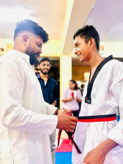 A smile of accomplishment as this student receives his red and black belt.