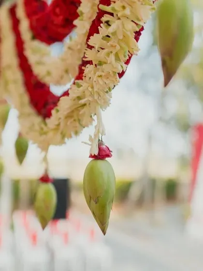 A unique traditional detail: fresh green mangoes hanging from a floral garland, symbolizing prosperity and fertility.