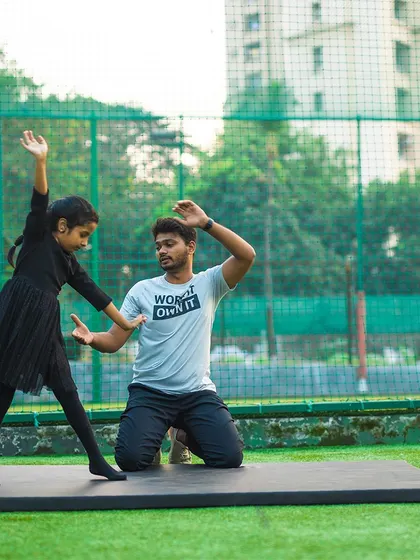 A young girl practices her gymnastic poses with a coach. I focus on making learning fun while building discipline and grace.