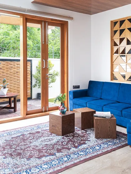 A view from the living room of the Cube House out to the patio. The design emphasizes indoor-outdoor flow with large sliding glass doors and a consistent, nature-inspired material palette.