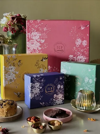 A festive spread featuring our colorful Artisan's Collection boxes. These chic, reusable boxes are filled with our signature tea cakes, gourmet cookies, and premium nuts.
