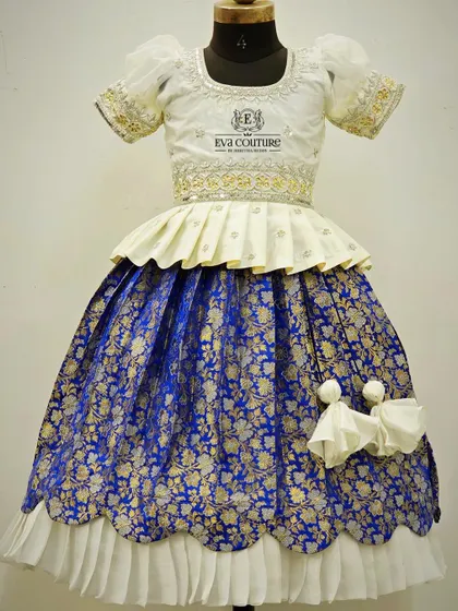 A variation of our popular Banarasi lehenga set for sisters, this one features a scalloped peplum top. The royal blue and white combination is timeless and elegant for any festive event.