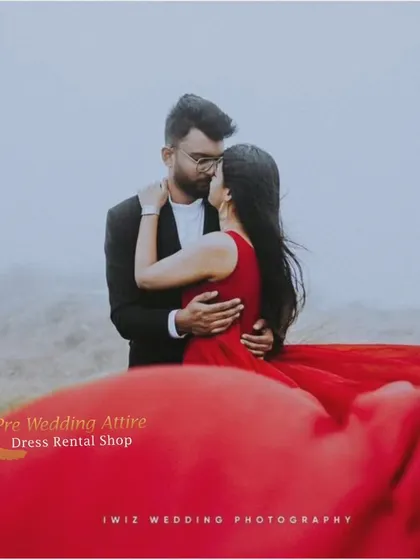 An intimate close-up of a couple in a misty, atmospheric setting. The focus is on their connection, with the vibrant red of the trail gown adding a pop of color.