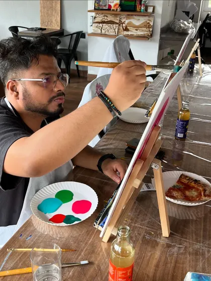 A focused painter working on his canvas, with a plate of pizza nearby. Art and snacks are a winning combination in our book.