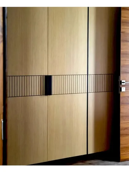 A walk-in wardrobe with a minimal and elegant veneer finish, featuring a subtle linear metal inlay.