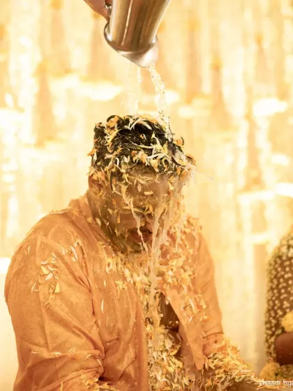 A dramatic shot of the groom getting drenched with water during the haldi, a fun ritual to wash it all off.