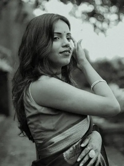 A candid black and white portrait. The model adjusts her hair with a gentle expression, creating a natural and spontaneous moment that feels authentic and unstaged.