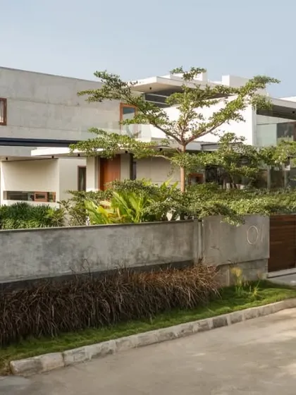 Viewed from the street, The Quarry House presents a layered facade of concrete, glass, and greenery. The boundary wall, constructed from the same concrete, integrates seamlessly with the main structure and the thoughtfully designed landscape.