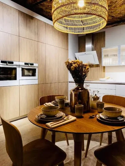 An open kitchen plan can make a small home feel much larger. This design uses warm wood cabinetry that covers an entire wall, seamlessly integrating the kitchen into the dining and living area.