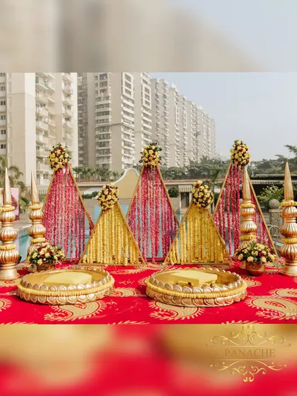 The main seating area for the Haldi ceremony, featuring traditional golden urlis and a backdrop of triangular panels adorned with marigold and rose petals.