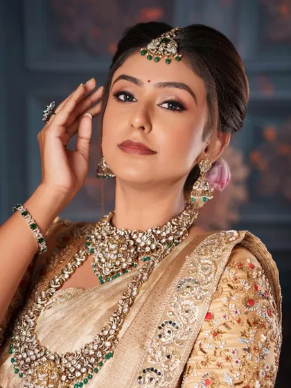 A close-up of the model, showing the intricate details of the Polki choker, maang tikka, and earrings.