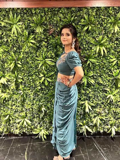 A side profile of our teal draped dhoti-saree, showcasing the intricate embroidery on the blouse and the flattering silhouette of the outfit.