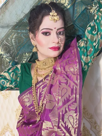 This look combines a purple and green Nauvari saree with traditional gold jewellery. The makeup features a pink and purple eyeshadow blend and a classic red lip.