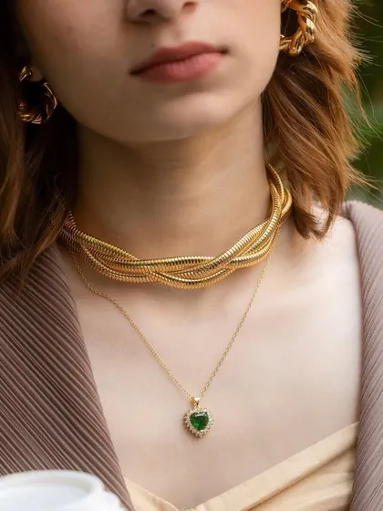 A close-up of our layered necklace look. The chunky rope choker paired with a delicate emerald heart pendant creates a perfect balance of bold and elegant.