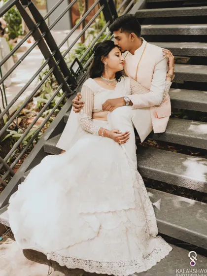 A romantic portrait of the couple on a staircase, with the groom kissing the bride's forehead.