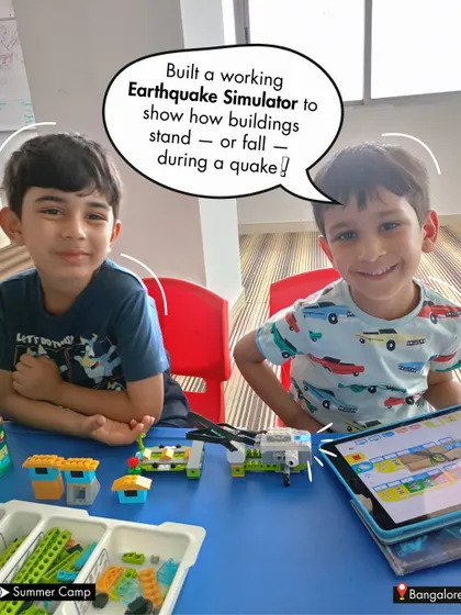 Two students proudly present their working Earthquake Simulator. This project taught them about structural stability and seismic waves in a hands-on, memorable way.
