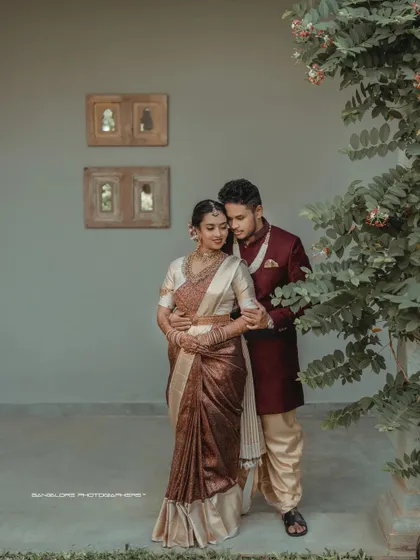 A portrait of poise and connection. The groom's rich maroon sherwani beautifully complements the bride's earthy-toned saree, captured at the elegant Amitarasa venue.