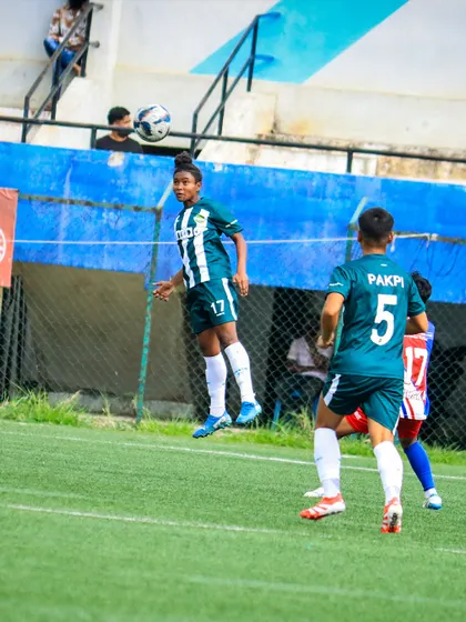 A young player leaps for a header, challenging for the ball in the air during a competitive Matchday 4 fixture.