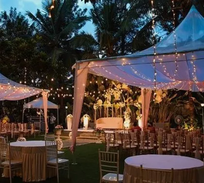 An elegant outdoor reception setup with tents, string lights, and beautifully arranged tables.