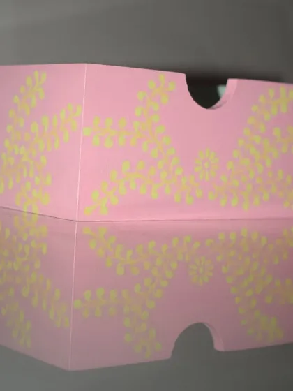 A side view of my hand-painted organizer, showing the delicate floral pattern against the pastel pink. The reflection highlights the smooth finish of this functional art piece.