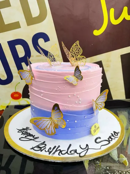 A 2kg cake with a pink and purple ombre buttercream finish, decorated with elegant gold-accented butterflies.