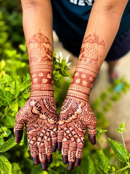 The fully developed, dark stain of an Ambari elephant bridal mehendi, photographed against a natural green background.