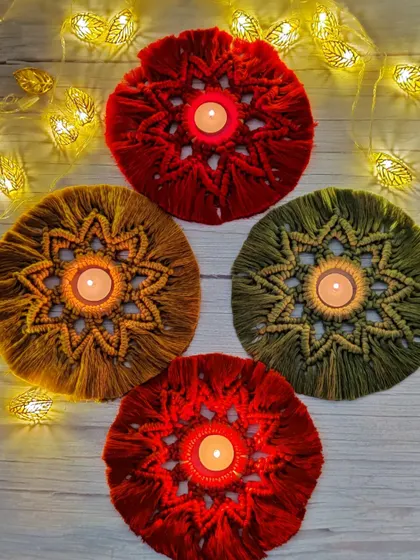 Another view of the macrame candle holders, glowing warmly with fairy lights in the background.