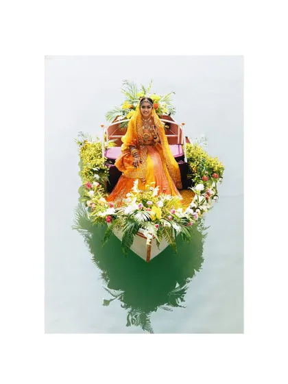 A breathtaking and unique bridal entry. The bride sits in a boat lavishly decorated with flowers, creating a surreal and unforgettable portrait that is both grand and serene.
