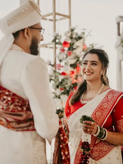 Beautiful captures from the Varmala ceremony. The bride's look is simple and elegant, with a classic red and white saree.