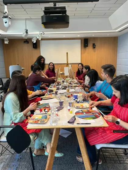 A lively table of Google employees fully engaged in the painting process. These workshops are designed to be fun and accessible, helping everyone unwind and express their creativity.