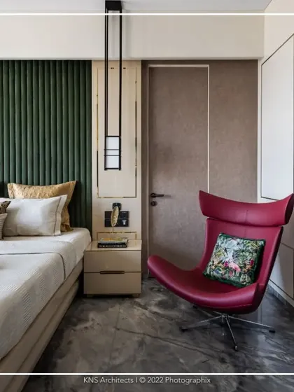 This bedroom design demonstrates how subtle luxury can make a bold statement. Warm color tones on the walls are complemented by grey marble flooring and a striking red accent chair, creating a space that is both sophisticated and visually dynamic.