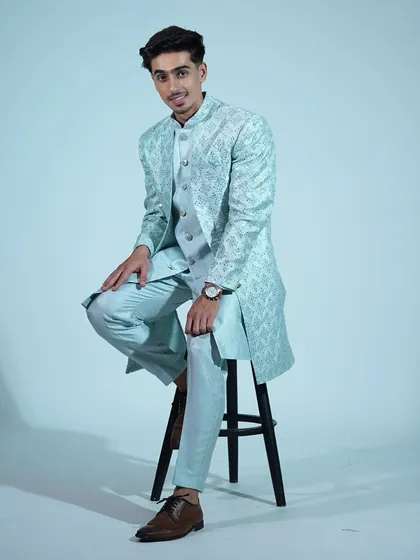 A seated pose in the light blue sherwani, showing how comfortable and stylish it is.