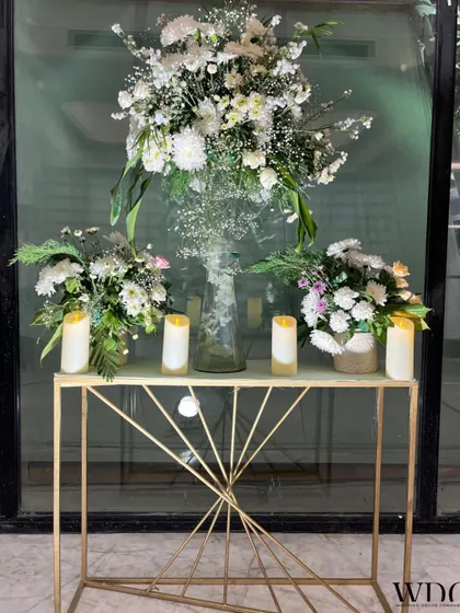 A simple yet stunning floral arrangement on a modern golden console table. The white flowers and LED candles create a calm and sophisticated vibe.
