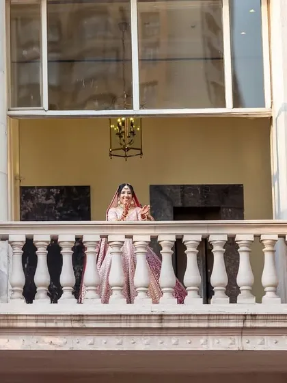 A "Juliet" shot of the bride on a balcony, looking down with a playful expression, as if waiting for her groom. A romantic and creative perspective.