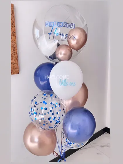 A cute balloon bunch to welcome a little one. The confetti and mix of blue, rose gold, and white balloons create a playful and celebratory feel.