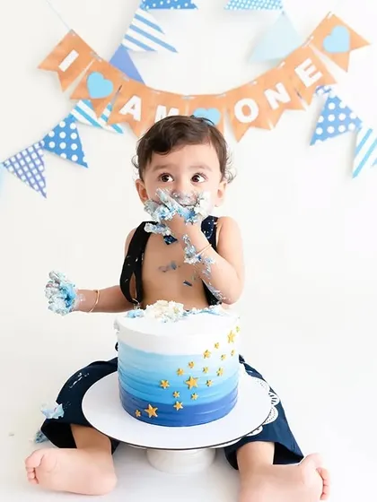 Capturing the baby's focused expression as he enjoys his first birthday cake.