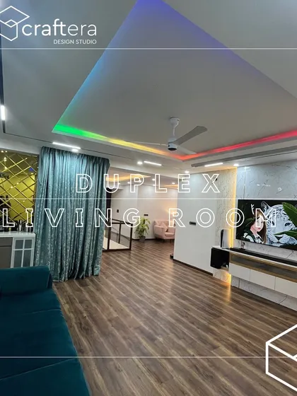 An expansive view of a duplex living room. The design features beautiful wooden flooring, a modern TV unit, and a false ceiling with customizable RGB cove lighting to set different moods for any occasion.