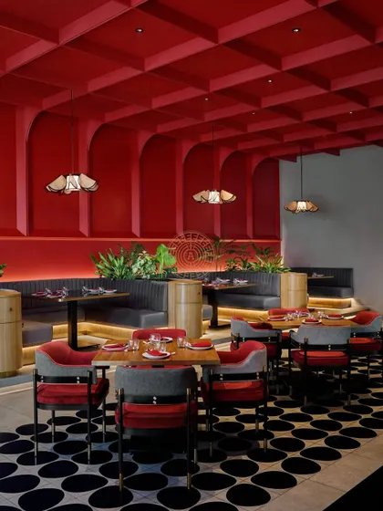 The combination of the red coffered ceiling, geometric floor, and varied seating creates a rich, layered design that is full of energy.