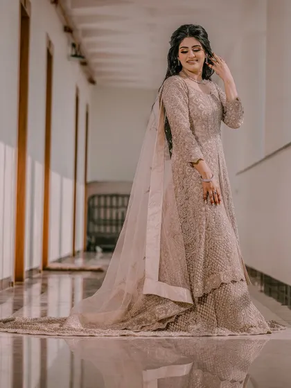 The bride looks down at her flowing gown, captured in a full-length shot that emphasizes the elegance of her attire.