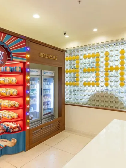 Inside the Borivali store, I designed a feature wall using the brand's iconic ghee jars to spell out "PDF," creating a fun, Instagrammable moment. The vibrant red product display next to it draws the eye and showcases the products beautifully.