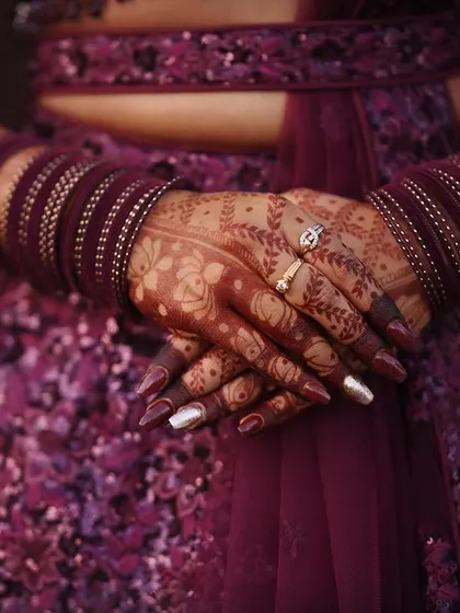 The beauty of a fully developed henna stain. The deep maroon color of the design perfectly complements the client's sequined lehenga and matching bangles.