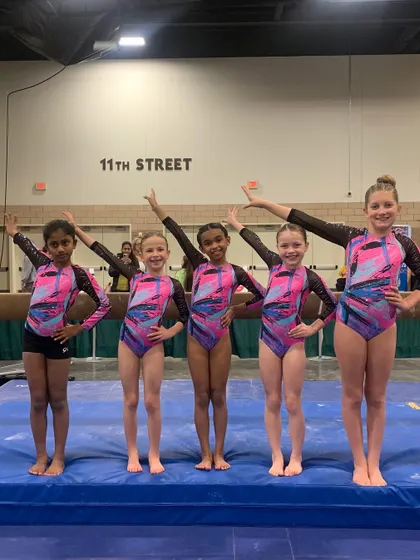 A group of our Xcel gymnasts striking a pose on the mats during the Metroplex Challenge.