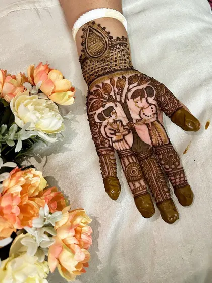 A single hand adorned with a beautiful couple portrait under a tree. This is a wonderful way to symbolize the growth of your relationship in your mehndi design.