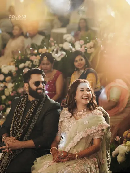 A candid shot of the couple enjoying a performance during their reception, their faces lit up with laughter.