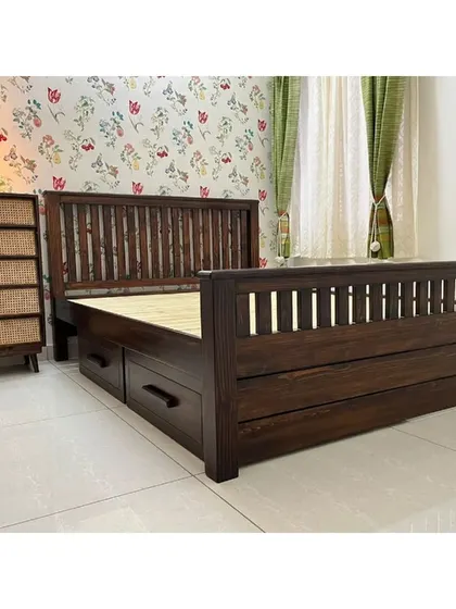 This bedroom showcases a solid dark wood bed with mission-style headboard and footboard, paired with drawers underneath for practical storage.