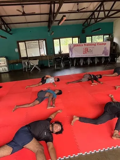 Flexibility is crucial for preventing injuries and executing advanced techniques. This image shows our athletes in a deep stretching pose, working on their hip and leg flexibility as part of our integrated yoga for fighters program.