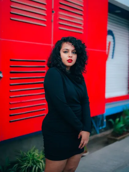 A duplicate of image 77, this portrait of a model in a black dress against a red wall is bold and confident.