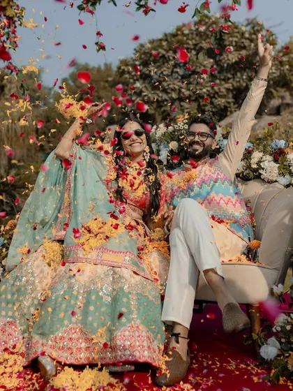 A celebratory shot of the couple being showered with flower petals during their Mehendi ceremony, capturing a moment of pure bliss.